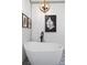 Modern white freestanding bathtub beneath a decorative light fixture and fern artwork on shiplap wall at 275 Crowe Springs Nw Rd, Cartersville, GA 30121
