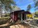 Low angle of a red house showing the front porch and a yard covered in leaves at 6475 Church St, Atlanta, GA 30291