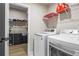 Laundry room with modern washer and dryer units, shelving, and storage for laundry essentials at 2436 Hidden Creek Road, Kennesaw, GA 30152