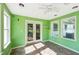 Cozy sunroom showcasing green walls, tiled floor, ceiling fan, and glass doors leading to an outdoor patio at 3880 Dial Mill Ne Rd, Conyers, GA 30013