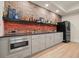 Wet bar featuring exposed brick wall, mini fridge, gray cabinets, and wood flooring at 107 Owens Mill Place, Canton, GA 30115