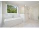 Modern bathroom featuring a soaking tub and glass-enclosed shower with window at 107 Owens Mill Place, Canton, GA 30115