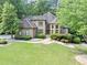 Well-manicured lawn leading up to a stately home with a grand entrance and meticulously landscaped grounds at 1455 Lockridge Dr, Cumming, GA 30041