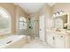 Elegant bathroom featuring a soaking tub, glass-enclosed shower, arched window, and vanity with a marble countertop at 710 Eastbourne Ct, Alpharetta, GA 30005
