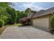 Home exterior with a large driveway and a two-car garage, complemented by lush landscaping and mature trees at 710 Eastbourne Ct, Alpharetta, GA 30005