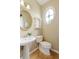 Cozy powder room with pedestal sink, wood floors, and decorative shelving at 710 Eastbourne Ct, Alpharetta, GA 30005