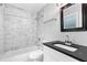 Well-lit bathroom featuring a modern vanity, toilet, and tub with marbled tile surround at 969 Oak Sw St, Atlanta, GA 30310