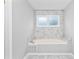Relaxing bathtub with marble tile surround and window, bathed in natural light at 969 Oak Sw St, Atlanta, GA 30310