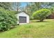 Detached garage in a grassy yard surrounded by lush greenery and trees at 30 Dewey Se Ln, Marietta, GA 30060
