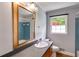 Bathroom featuring a vintage vanity with modern countertop, large mirror, and a window providing natural light at 385 Vineyard Nw Dr, Marietta, GA 30064