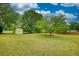 Spacious backyard with lush lawn, mature trees, and a small yellow shed at 205 Summer Walk Dr, Covington, GA 30016