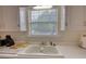 Kitchen sink area with white cabinets, laminate countertops and natural light streaming in from the window at 205 Summer Walk Dr, Covington, GA 30016