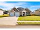 Charming brick home featuring a two-car garage, manicured lawn, and a welcoming facade under a clear blue sky at 1341 Midnight Ride Ct, Hampton, GA 30228