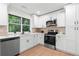 Modern kitchen with stainless steel appliances, quartz countertops, white cabinetry, and a large window at 1490 Diplomat Dr, Riverdale, GA 30296