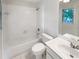 Well-lit bathroom with a shower-tub, window, and white tile and fixtures at 9979 Bridgewater Pointe, Villa Rica, GA 30180