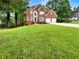 A beautiful brick two-story home, showcasing mature trees, an expansive front lawn, and a two car garage at 9979 Bridgewater Pointe, Villa Rica, GA 30180