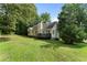 Back exterior view of home featuring a deck and grassy area, with mature trees and landscaping at 136 Walkers Pond Dr, Villa Rica, GA 30180