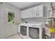 Bright laundry room with a window door, white cabinets, and modern washer and dryer units at 1732 Samaria Trl, Tucker, GA 30084