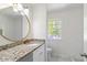 This bathroom shows a vanity with granite top, gold fixtures, round mirror and tiled floors at 1129 Pinehurst Rd, Grayson, GA 30017