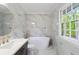 Bathroom featuring modern tub, marble-look tile, and window at 1129 Pinehurst Rd, Grayson, GA 30017