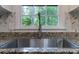 Close up of stainless steel kitchen sink with granite countertops and white backsplash tiles at 1129 Pinehurst Rd, Grayson, GA 30017