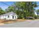 View of the charming white house with neat landscaping, set against a backdrop of mature trees and a quiet street at 130 South Se Ave, Marietta, GA 30060