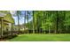 Lush green backyard, bordered by tall trees, features an expansive lawn and large patio at 1358 Peppergrass Nw Trl, Acworth, GA 30101