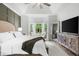 Bright primary bedroom with a tray ceiling, sitting area near a bay window, and entertainment center with a large TV at 1358 Peppergrass Nw Trl, Acworth, GA 30101