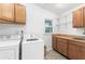 Bright laundry room featuring a washer, dryer, wood cabinets, butcher block counter and white shiplap at 3294 Mcclure Bridge Rd, Duluth, GA 30096