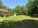 Expansive lawn with mature trees, a storage shed, and a partial view of the home at 7260 Cox Rd, Cumming, GA 30028