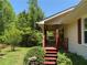 Cozy front porch features wooden posts, a swing and chairs, and steps framed by lush greenery at 7260 Cox Rd, Cumming, GA 30028