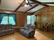 Inviting living room with wood-paneled walls, beamed ceiling, and comfortable seating arrangement at 7260 Cox Rd, Cumming, GA 30028