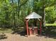 Unique well feature with a decorative shelter and wooden construction in a lush wooded area at 7260 Cox Rd, Cumming, GA 30028