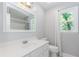 This bathroom features a mirror, vanity, toilet, window, white walls, and tile flooring at 1463 Shadowrock Hts, Marietta, GA 30062