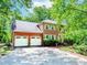 Charming two-story brick home featuring a spacious driveway and a two-car garage surrounded by lush trees at 1463 Shadowrock Hts, Marietta, GA 30062