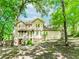 Two-story home with light yellow siding and covered porch, surrounded by mature trees at 1463 Shadowrock Hts, Marietta, GA 30062