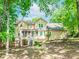 A light-yellow two-story home with a covered porch and bay window, nestled among lush greenery at 1463 Shadowrock Hts, Marietta, GA 30062