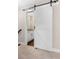 Modern bathroom with barn door, granite countertop, white cabinets, and wood floors at 1874 Mcgarity Rd, Mcdonough, GA 30252