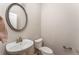 Half bathroom features a pedestal sink, modern faucet, a toilet and a decorative oval mirror at 2167 Crestridge Ne Trl, Brookhaven, GA 30329