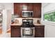 Close-up of the kitchen featuring a stainless steel oven and microwave, granite countertops, and dark wood cabinets at 2771 Stonecreek Se Rd, Smyrna, GA 30080