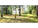 Large grassy backyard showcasing mature trees and the rear exterior of the home at 60 Whispering Pine Ct, Covington, GA 30016