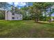 Large, grassy backyard with a view of the home's exterior and surrounding trees at 60 Whispering Pine Ct, Covington, GA 30016