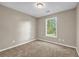 A simple, carpeted bedroom features neutral walls and a window providing natural light and views of the outdoors at 60 Whispering Pine Ct, Covington, GA 30016