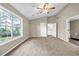 A spacious bedroom with neutral walls, plush carpet, vaulted ceiling, and a bright window with tree view at 60 Whispering Pine Ct, Covington, GA 30016