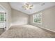 A large bedroom with neutral walls, plush carpet, a ceiling fan, and a bright window offering natural light at 60 Whispering Pine Ct, Covington, GA 30016
