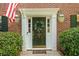 Close-up of a front door with a wreath, sidelights, an American flag, and lanterns at 815 Lake Forest Pass, Roswell, GA 30076