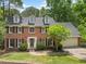 Charming brick home featuring a manicured lawn, lush landscaping, and a welcoming front entrance at 815 Lake Forest Pass, Roswell, GA 30076