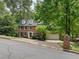 Classic brick home with a two-car garage, dormer windows, and mature trees in a serene setting at 815 Lake Forest Pass, Roswell, GA 30076