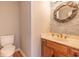 Stylish half bathroom with wood cabinets, modern fixtures, and a decorative mirror at 130 Brandon Mill Cir, Fayetteville, GA 30214