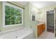 Bright bathroom featuring a soaking tub under a window and double vanity with granite countertops at 2114 Lindley Nw Ln, Kennesaw, GA 30144